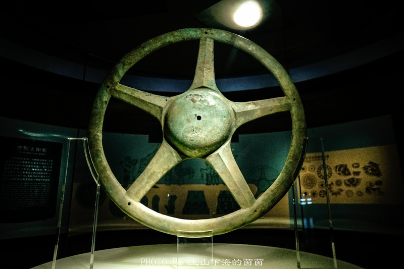 青铜太阳轮:构型为圆形,直径85厘米左右,正中阳部凸起,其周围五芒的布