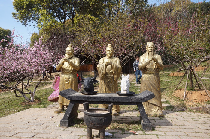 桃园中摆放了刘关张三人的铜像,呈现出桃园三结义的场景