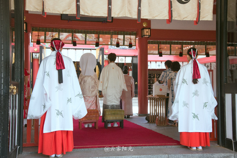 身着白衣红裙的神官示意围观的人们让开道路,新人就要走出神社接受