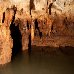 Stalactites in stone cave with underground river or lake