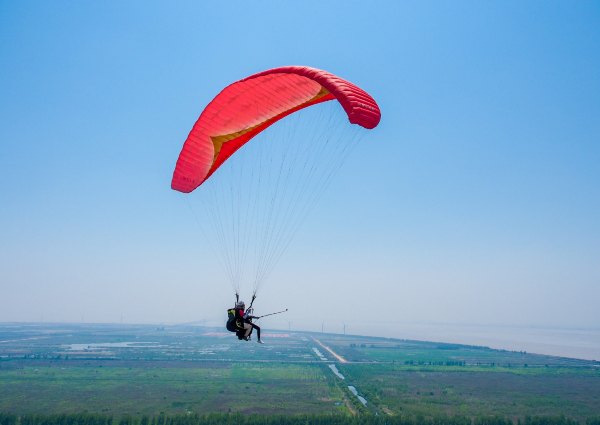 一边拿着自拍杆,一边和教练聊天,这般体验也只有滑翔伞能感受到