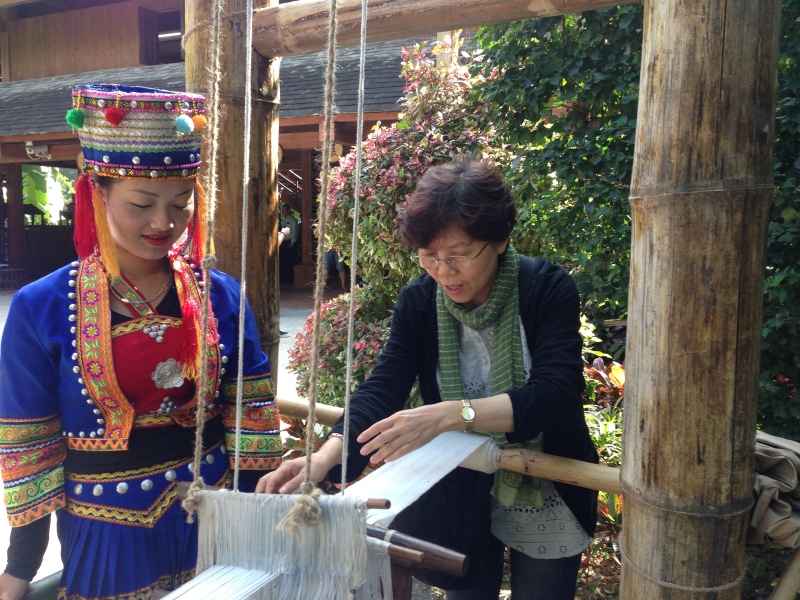 参观傣族村寨傣族姑娘小玉把游客请到家里介绍以前家里使用过的劳动