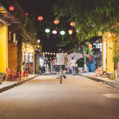 Cyclist male in Hoi An traditional street by night in summer with lanterns