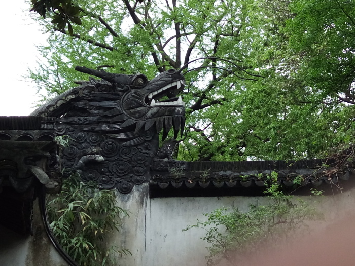 院落间的长廊上有一个龙头,蔓延着整个龙身在墙上,像是长龙盘卧,龙