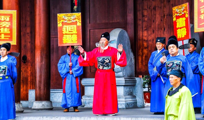 肃静","回避"牌子鸣锣开道,知府大人在中间骑着大马,文武官员尾随其后
