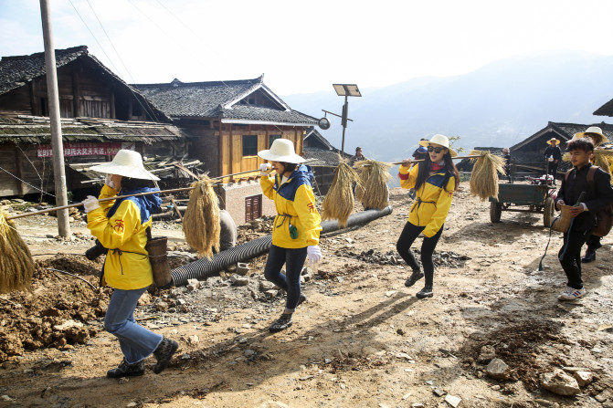 先是把稻穗绑在扁担上,抬到下面的梯田的一个架子上挂好.
