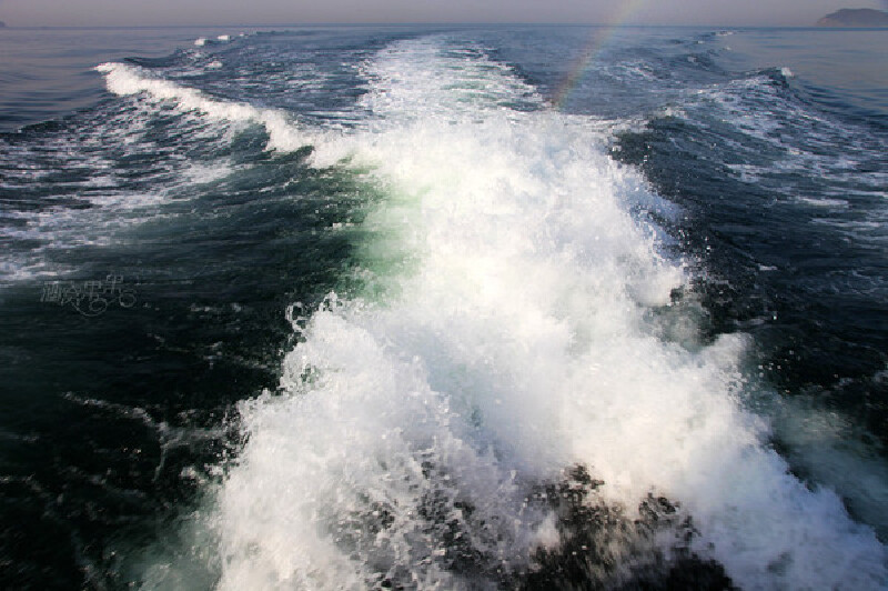 船尾的浪花像海星一样,光折射出美丽的彩虹