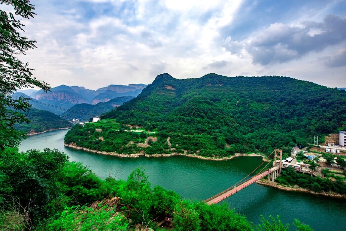 远处的鹊桥,大坝,在绿树环绕,烟波浩淼的京娘湖                    .