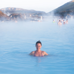 Woman relaxing in geothermal spa in hot spring pool in Iceland. Girl enjoying bathing in a blue water lagoon with famous healing mud.