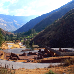a paved road goes in a hairpin bend around an excavation site of the inca culture in the sacred valley in peru, in the background is the typical mountain landscape of this area
