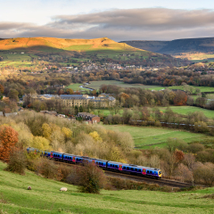 Passenger train passing through british countryside near greater Manchester, England.