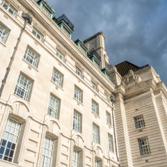 County Hall buildings, located along river Thames in London, England, under rainy cloudy sky