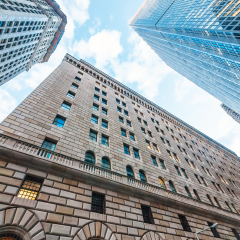 The Federal Reserve Bank of New York, upward view, and surrounding buildings.