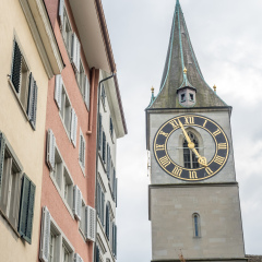 Saint Peter church clock tower with surrounding buildings under cloudy sky in Zurich, Switzerland