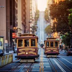 Classic view of historic traditional Cable Cars riding on famous California Street in morning light at sunrise with retro vintage style cross processing filter effect, San Francisco, California, USA