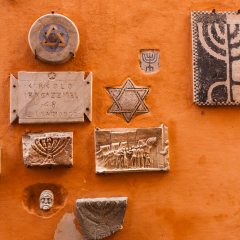 Jewish sculptures on a wall with menorah mosaic