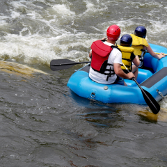 A family splashes into the St Joseph river in a raft at the east race water course in south bend Indiana. this was the first men made course in north America, opening in 1984.