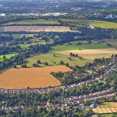 Aerial view of Osterley Park surrounded by trees, fields and clusters of houses in in London outskirts, England