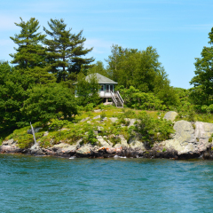 Island with house, cottage or villa in Thousand Islands Region in sunny summer day in Kingston, Ontario, Canada. 1000 Islands near Gananoque, ON. Famous Canadian tourist vacation routs.