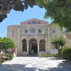 Church of Panagia Ekatontapiliani in Parikia, typical front entrance view with tree branches in sunny day with a few blurry unrecognizable tourist, Paros island, Cyclades, Greece