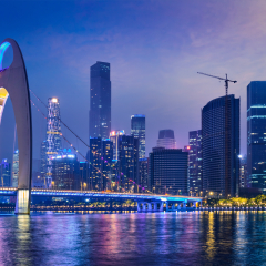 Guangzhou cityscape skyline over the Pearl River with Liede Bridge illuminated in the evening. Guangzhou, China