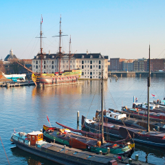Houseboats on the Amstel river in Amsterdam, Netherlands. National Maritime Museum on the background 