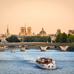 Seine River in Paris with Passerelle de Solferino bridge. In the distance, Notre Dame Cathedral in summer evening light. France