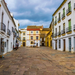 view of the small square Plaza del potro in the spanish city cordoba, which is surrounded by many restaurants, tourist shops and an ancient fountain.