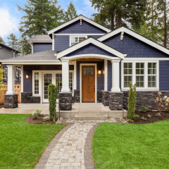 Beautiful exterior of newly built luxury home. Yard with green grass and walkway lead to ornately designed covered porch and front entrance. 