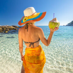 Woman With Coconut Standing At Beach Against Sky