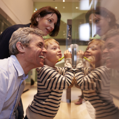 Family Looking At Artifacts In Glass Case On Trip To Museum