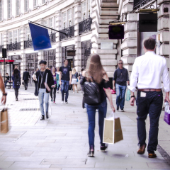 People walking down busy high street with shopping bags.