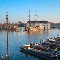 Row of houseboats on the Amstel river in Amsterdam, Netherlands. National Maritime Museum on the background 