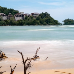 Sea tide waves and big abandoned hotel in the background. Thailand. Phuket. Nai yang beach