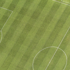 Aerial view over nicely cut grass of soccer field, with central circle