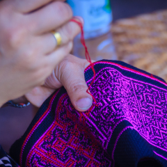 Close up hand of Hmong woman is sewing traditional tribal clothes with sewing needle and thread at Doi Pui’s Hmong ethnic hill-tribe village, Chiang Mai, Thailand.