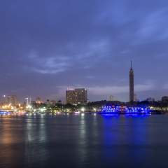 Cairo city center at twilight, the Kasr El Nile Bridge and the island of Zamalek with its colorful boats on the Nile river.