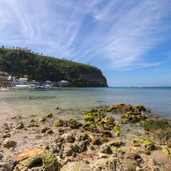 Seascape of beach with transparent sea, blue sky, palms and boats.Taken at Sabang, Puerto Galera, Mindoro island, Philippines, popular tourist and diving spot. Reminds of heaven or travel of dream.