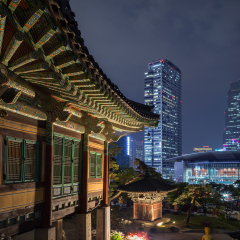 Ornate building at the Bongeunsa Temple and view of Gangnam in Seoul, South Korea at night.