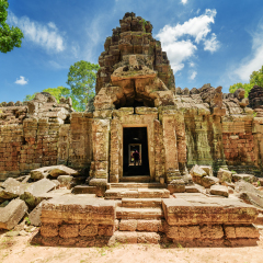 One of entrances to ancient Ta Som temple on blue sky background. Enigmatic Ta Som nestled among rainforest in amazing Angkor, Siem Reap, Cambodia. Mysterious Angkor is a popular tourist attraction.
