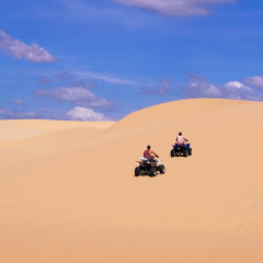 People chasing around sand dunes on a quad bike Mui Ne, Vietnam