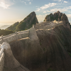 A walking trail at the very top of Huangshan mountain during sunrise with its typical pines and granite peaks. Famous Lotus peak at the background. Anhui province, Eastern China.
