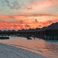 NORTH MALE, MALDIVES -6 JUL 2018- Sunset over the luxury over-the-water bungalows with thatched roofs at the Sheraton Maldives Full Moon Resort & Spa hotel on Furanafushi Island, North Malé Atol.