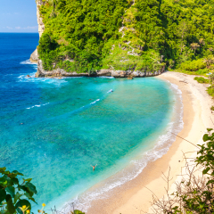 Top view on paradise azure beach with rocky mountains, green palm trees and clear water of Indian ocean at sunny day / A view of a cliff in tropical island Bali Indonesia / Bali, Indonesia