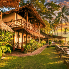 Traditional native style beachfront resort property with thatch roof on tropical island in southeast asia during beautiful sunrise.