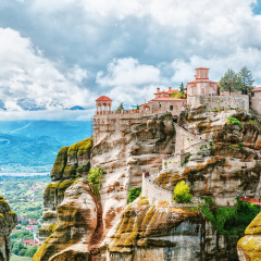 Monastery Meteora Greece. Stunning summer panoramic landscape. View at mountains and green forest against epic blue sky with clouds. UNESCO heritage list object.