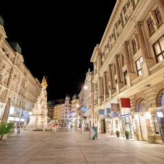 Pestsaule between illuminated buildings during night at Graben street in Vienna, Austria 
