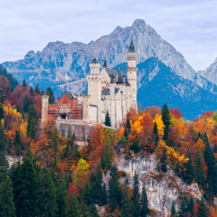 Beautiful autumn scenery of Neuschwanstein Castle with colorful autumn trees and the Alps on background. Bavaria, Germany.