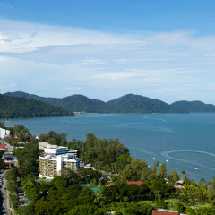 Aerial view of Batu Ferringhi Beach and Penang National Park located in the Malacca Strait on Penang Island, Malaysia. Batu Ferringhi is a popular travel destination for tourism.