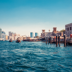 Skyline view of Dubai Creek with traditional boats and piers. Sunny summer day. Famous tourist destination in UAE. Creative color post processing.